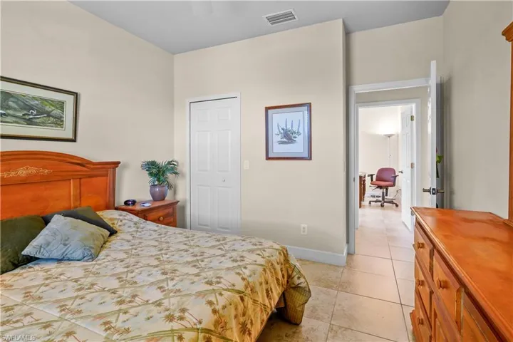 Bedroom with a walk-in closet, light tile patterned 20" porcelain tile flooring, 5 3/4' baseboard, 2" wood window blinds and a ceiling fan.