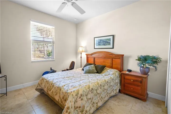 Guest bedroom features a walk-in closet, 2" white windo blinds, 5 3/4' baseboard and 20" porcelain tile and a ceiling fan.
