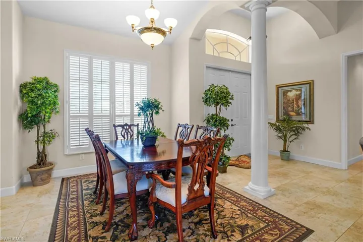 Beatuiful dining space with decorative columns and arched walkways, chandeliers, 20" porcilin tile floors, 5 3/4" base boards, large hurricane windows with wooden plantaion shutters.