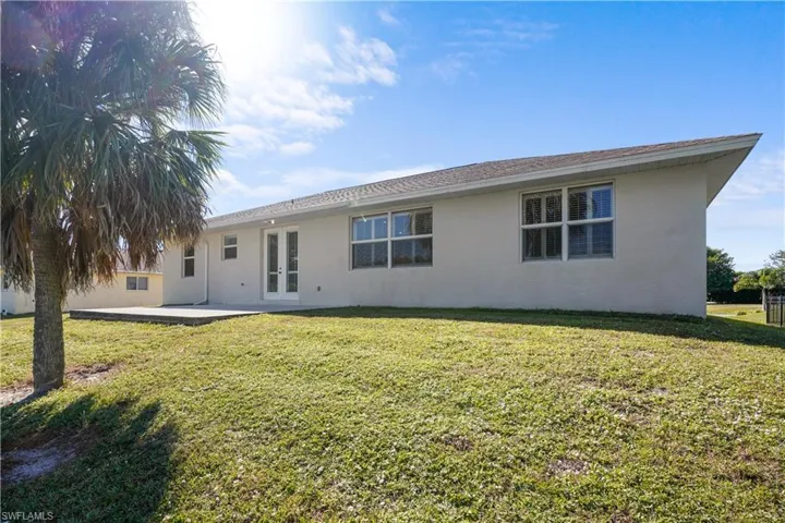 Rear view of house featuring a yard, stucco siding, and a patio
