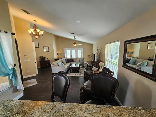 Living area with vaulted ceiling, a ceiling fan, and a chandelier