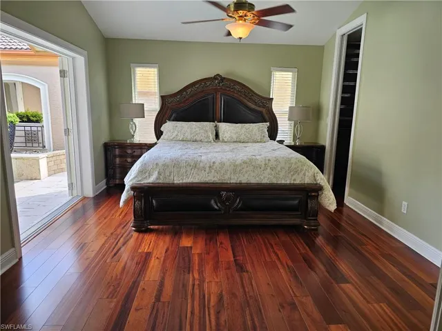 Bedroom featuring access to outside, multiple windows, dark wood-type flooring, a ceiling fan, and lofted ceiling