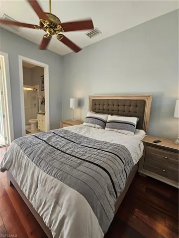 Bedroom with wood finished floors, ceiling fan, and ensuite bathroom
