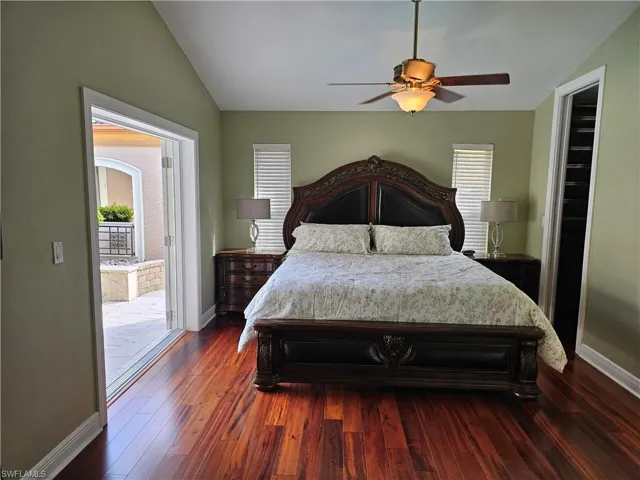 Bedroom featuring lofted ceiling, dark wood-type flooring, a ceiling fan, and access to outside