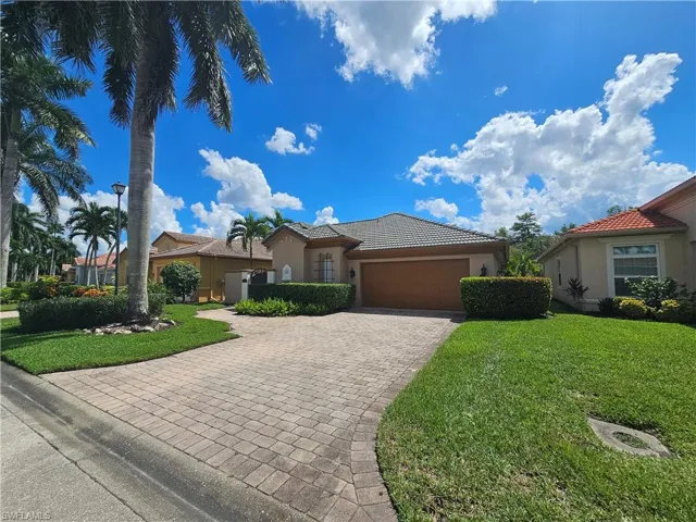 Mediterranean / spanish home featuring stucco siding, a front yard, a tile roof, and decorative driveway