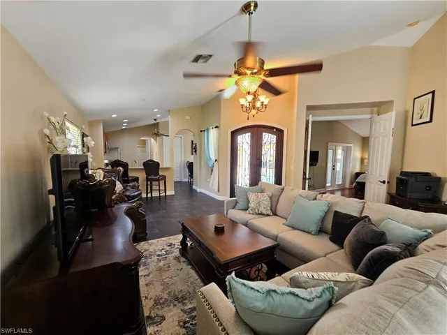 Living area with lofted ceiling, french doors, a ceiling fan, arched walkways, and recessed lighting