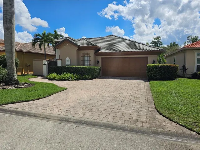 Mediterranean / spanish-style home featuring stucco siding, a tile roof, a gate, and decorative driveway