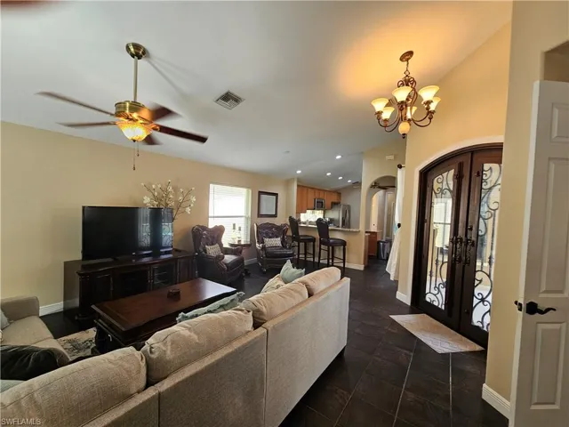 Living room with arched walkways, french doors, recessed lighting, a chandelier, and vaulted ceiling
