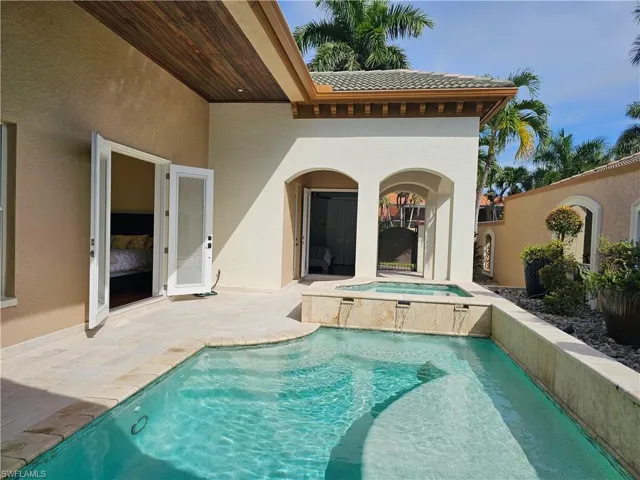 Rear view of house featuring a patio, a tile roof, stucco siding, and a pool with connected hot tub