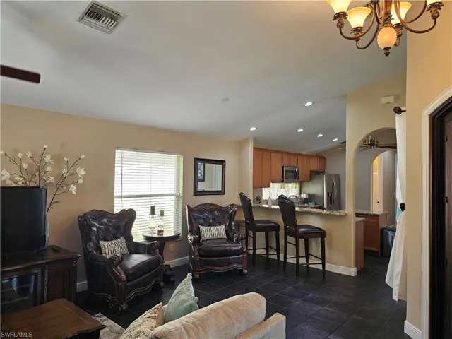 Living area featuring arched walkways, recessed lighting, ceiling fan, and a chandelier