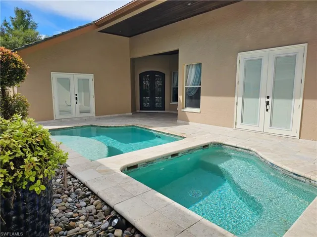 Swimming pool with french doors, a patio, and an in-ground hot tub