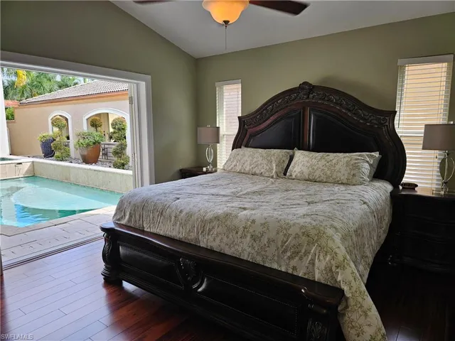 Bedroom featuring vaulted ceiling, hardwood / wood-style floors, access to outside, and ceiling fan