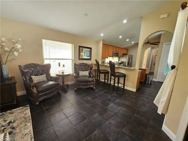 Living area with arched walkways, recessed lighting, and dark stone finish floors