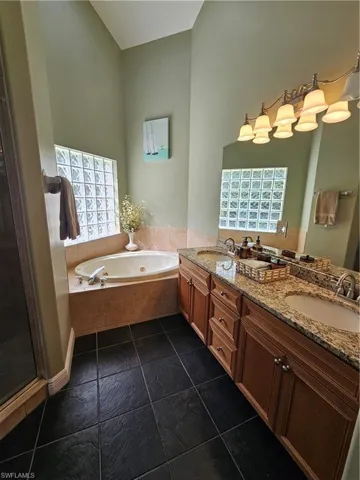 Bathroom featuring a whirlpool tub, double vanity, and a stall shower