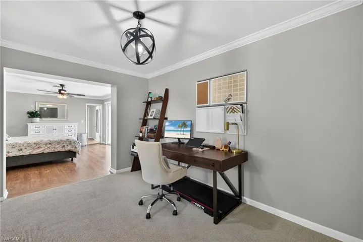 Carpeted office with ornamental molding, a ceiling fan, and a chandelier