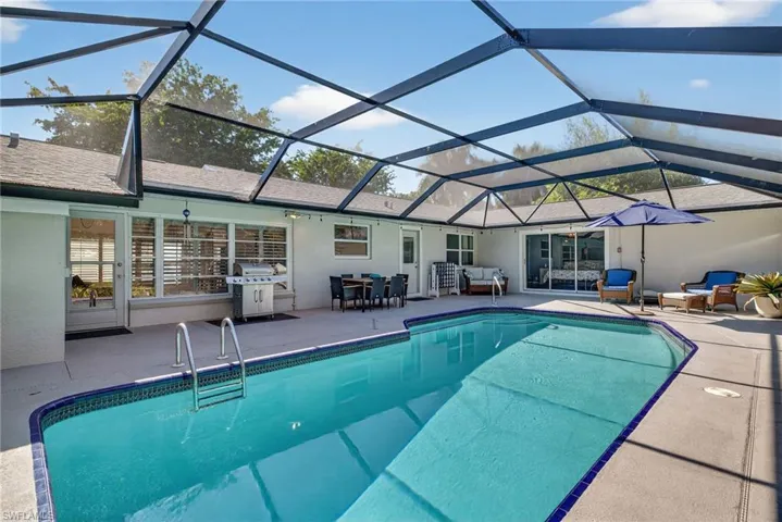 Swimming pool featuring outdoor lounge area, a sunroom, a lanai, a patio area, and area for grilling