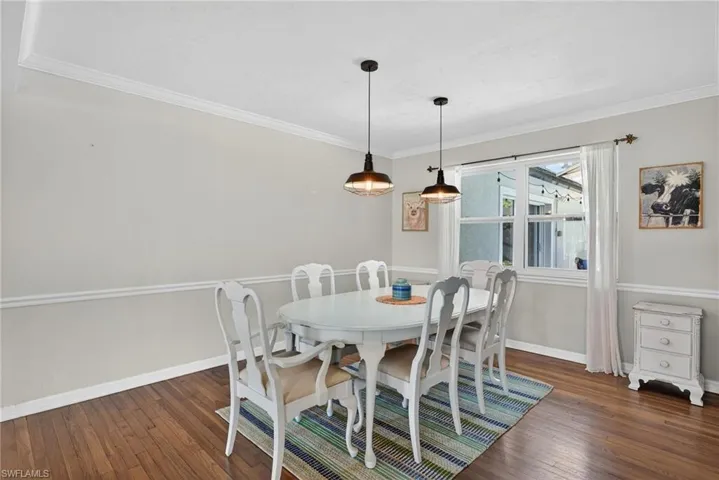 Dining space with ornamental molding and dark wood-type flooring