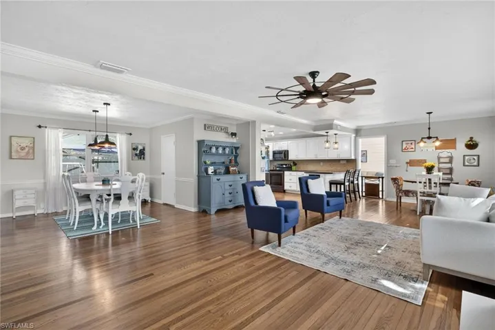Living room featuring crown molding, dark wood finished floors, and a ceiling fan