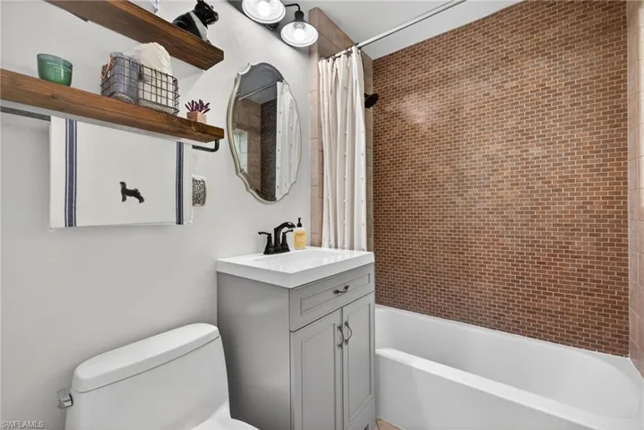 Full bath with shower / bath combination with curtain and vanity
