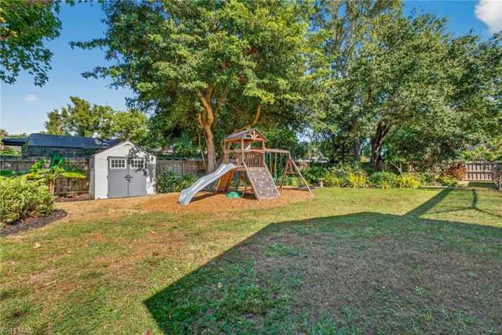 Fenced backyard with a storage shed and a playground