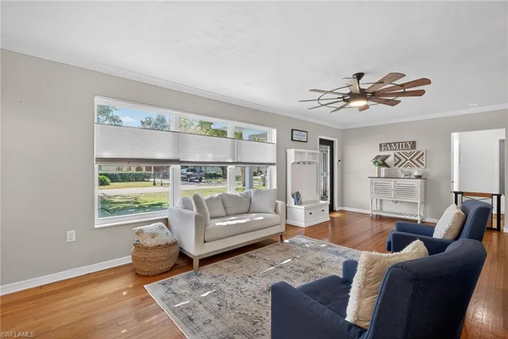 Living room with ornamental molding, light wood-style flooring, plenty of natural light, and ceiling fan