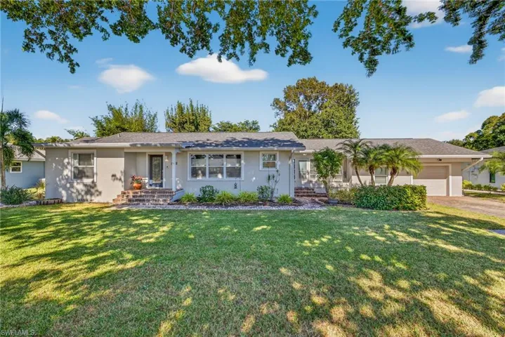 Ranch-style home featuring a front yard, stucco siding, and a garage