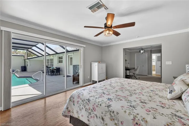 Bedroom featuring a sunroom, crown molding, light wood finished floors, multiple windows, and access to exterior