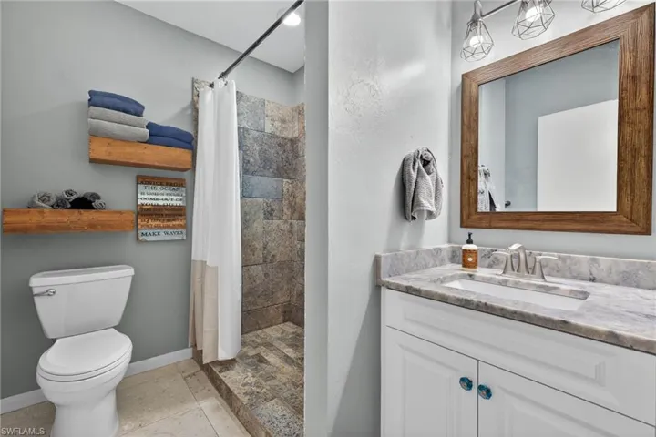 Full bathroom with a shower stall, vanity, and stone tile flooring