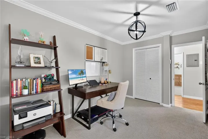 Office area with crown molding, light carpet, and electric panel