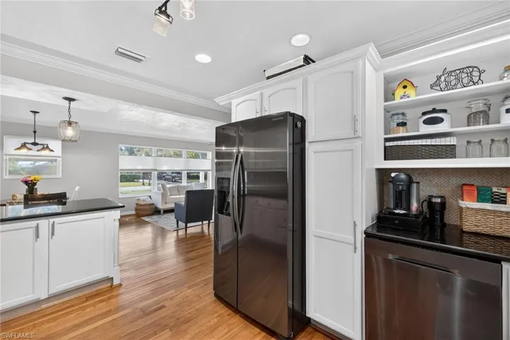Kitchen with crown molding, white cabinets, refrigerator with ice dispenser, stainless steel dishwasher, and open shelves