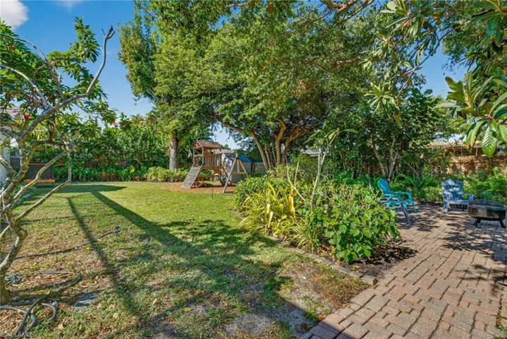 Fenced backyard with a playground and an outdoor fire pit