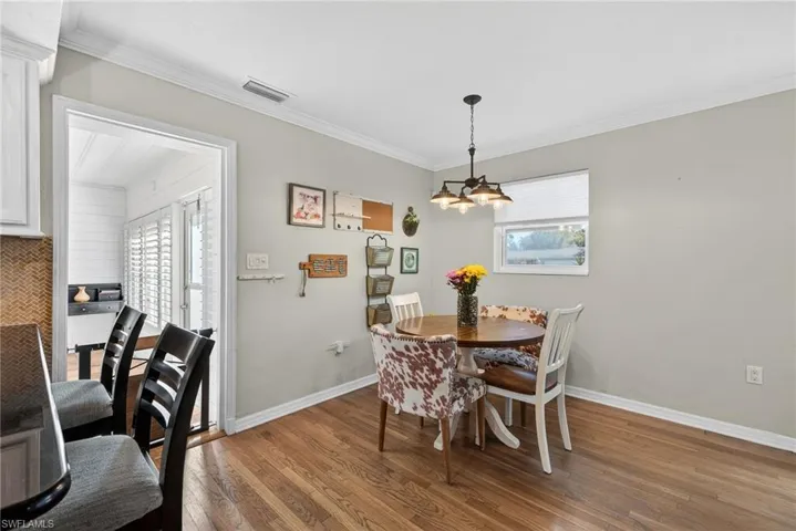 Dining room with light wood finished floors, crown molding, and a chandelier