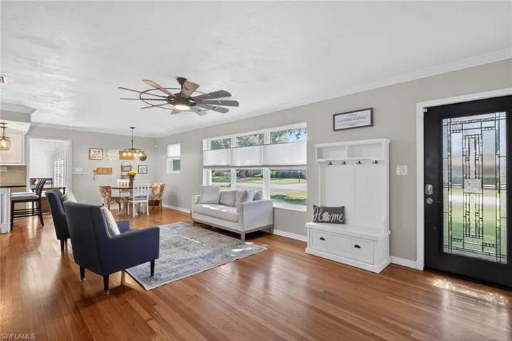 Living room with ceiling fan, crown molding, and light wood finished floors