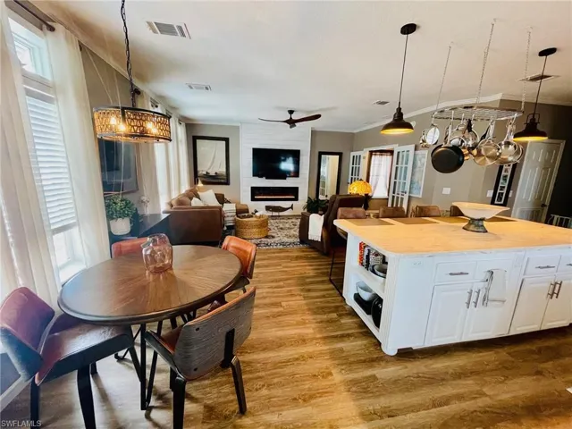 Kitchen featuring white cabinets, light wood-type flooring, ceiling fan with notable chandelier, decorative light fixtures, and a center island