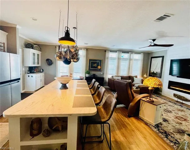 Dining space with a textured ceiling, ceiling fan, light wood-type flooring, and ornamental molding