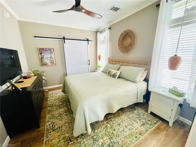 Bedroom featuring hardwood / wood-style floors, a barn door, and multiple windows
