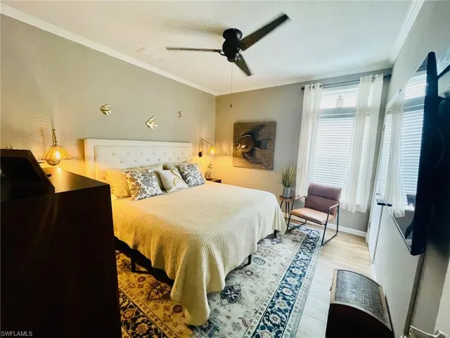 Bedroom featuring light hardwood / wood-style floors, crown molding, and ceiling fan