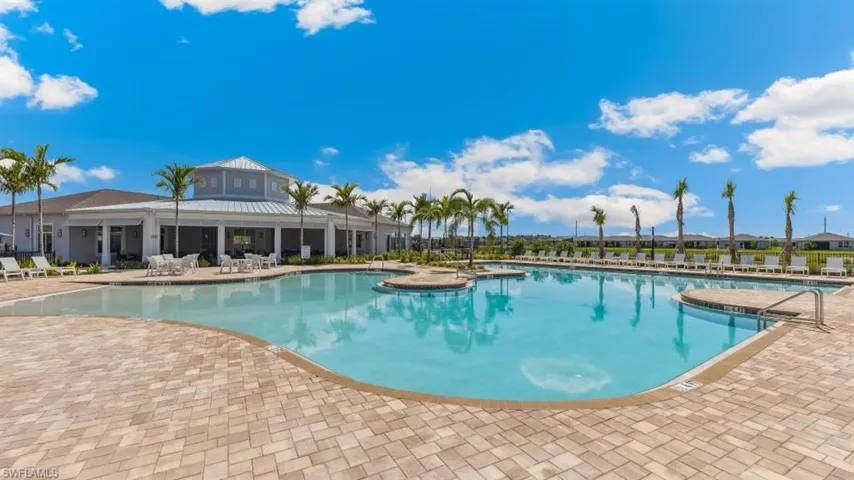 The property features a large outdoor pool with a paved deck, surrounded by palm trees and lounge chairs