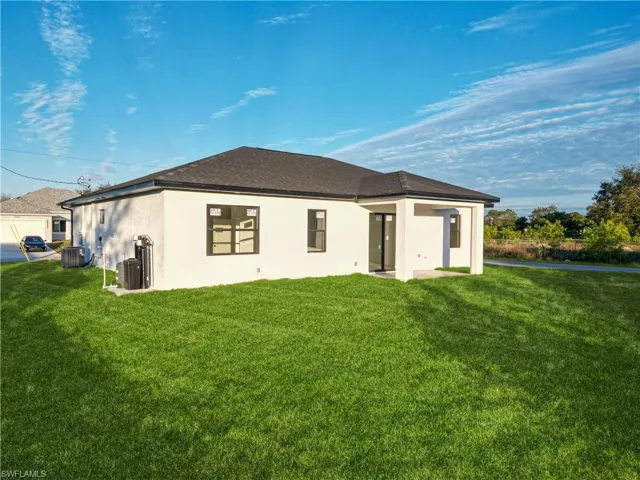 Back of house featuring a yard and cooling unit