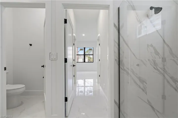 Bathroom featuring a shower with door and toilet