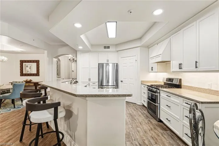 The kitchen features a breakfast bar, custom shaker-style cabinetry, and granite countertops, complemented by under-cabinet lighting and new recessed lighting, creating a bright and inviting space.