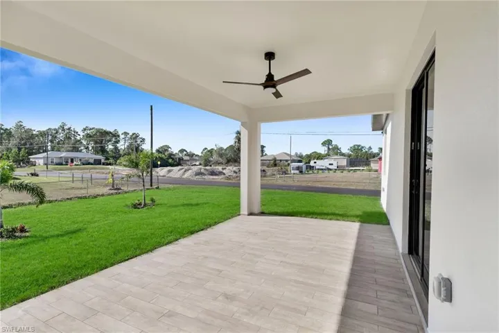 Covered patio featuring wood-finish tile flooring, a matte black ceiling fan, and access via sliding glass doors