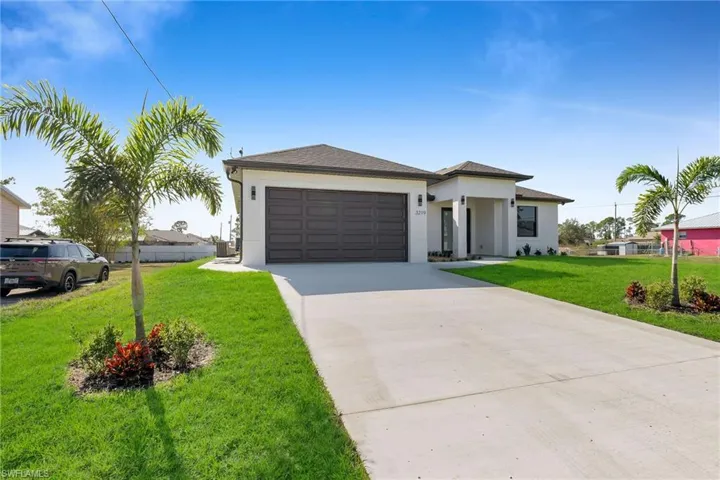 Contemporary single-story exterior featuring a hip roof, stucco facade, multi-panel garage door, and concrete driveway