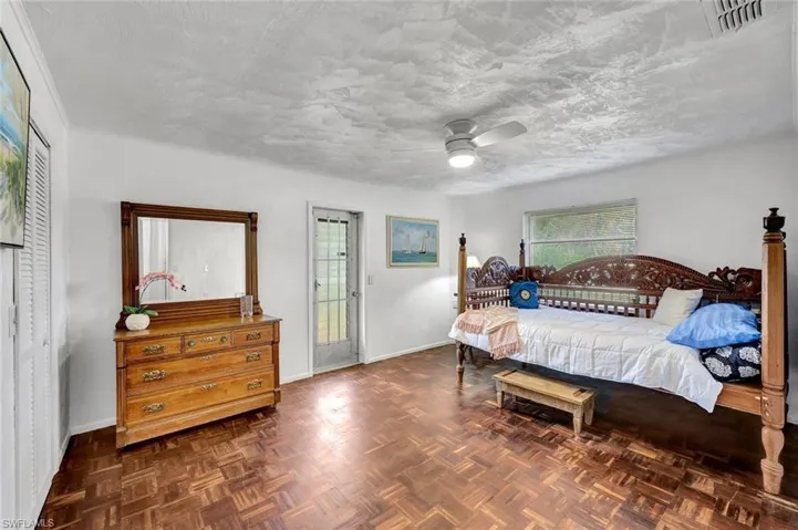 Large guest bedroom featuring ceiling fan and side entrance.