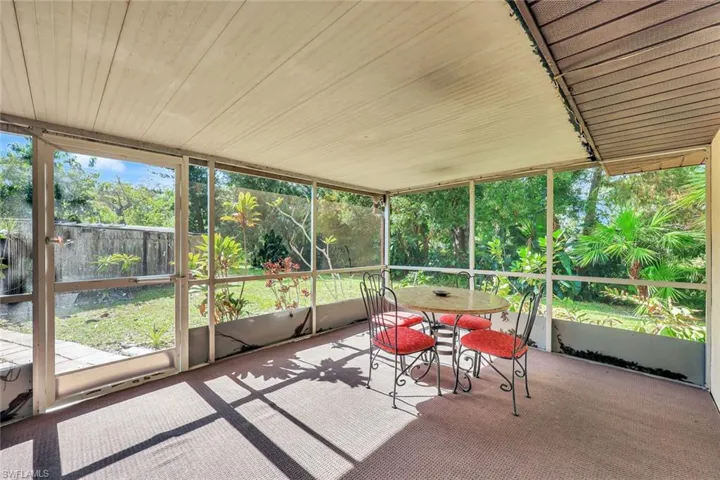 Large screened lanai on side of house with view of the yard and stream.