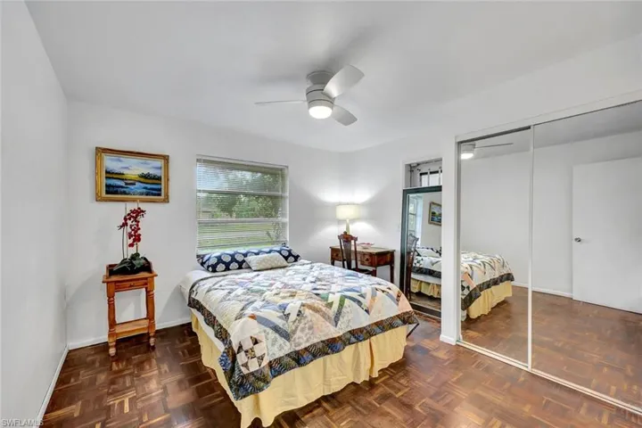 Primary bed-room with brazilain walnut flooring, ceiling fan, and closet with mirrored doors.