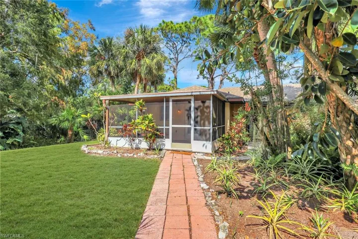 Side yard with large screened lanai and paved walkway.