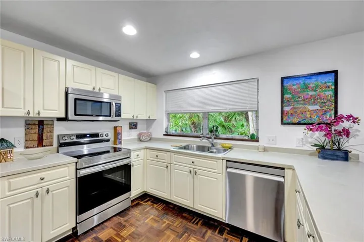 Kitchen with new stainless steel appliances, large window and Brazilian walnut flooring.