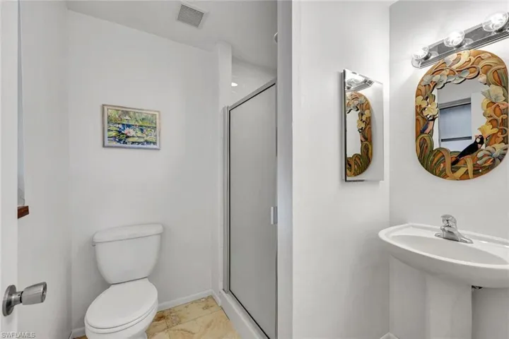 Guest bathroom with marble tile and walk-in shower and pedestal sink.