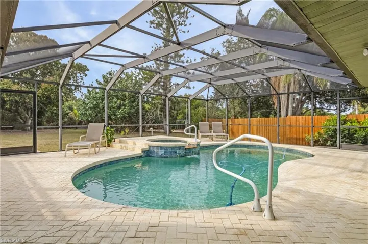 View of swimming pool featuring a lanai, a patio area, and an in ground hot tub